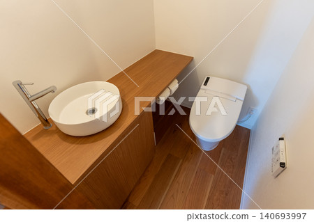 A modern toilet with a wood-grain counter and sink. A modern toilet with a wood-grain counter and sink. 140693997