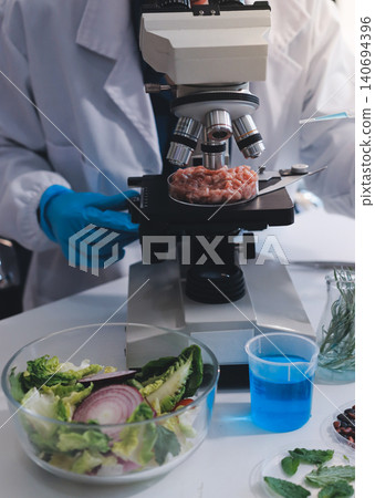 Scientists in lab coats work with plants in a modern lab, focusing on research and experimentation under bright, sterile conditions. Scientists in lab coats work with plants in a modern lab, focusing on research and experimentation under bright, sterile conditions. 140694396