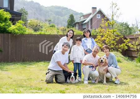 A three-generation family smiling together in the garden with their two beloved dogs. A three-generation family smiling together in the garden with their two beloved dogs. 140694756
