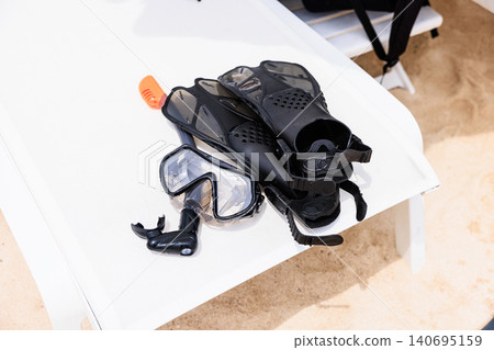A complete set of snorkeling equipment (mask, snorkel, and fins) placed on a beach chair. A complete set of snorkeling equipment (mask, snorkel, and fins) placed on a beach chair. 140695159