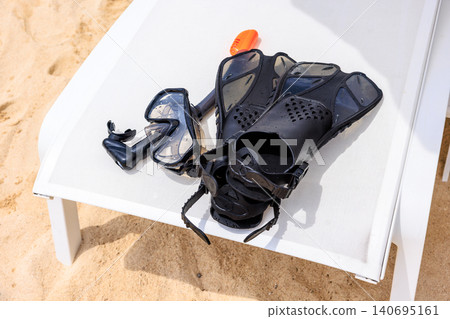 A complete set of snorkeling equipment (mask, snorkel, and fins) placed on a beach chair. A complete set of snorkeling equipment (mask, snorkel, and fins) placed on a beach chair. 140695161