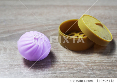 Anti-stress toy in the shape of a pink dumpling squishy lying near the box 140696518