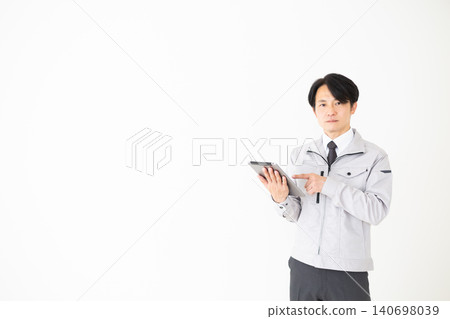 一位身穿灰色工作服的中年商務人士手持平板電腦,背景為白色。 一位身穿灰色工作服的中年商務人士手持平板電腦,背景為白色。 140698039