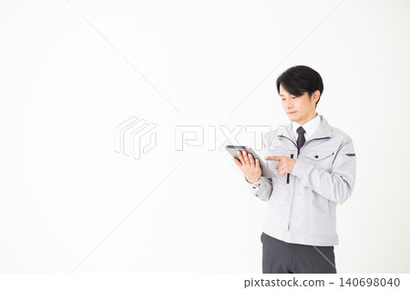 一位身穿灰色工作服的中年商務人士手持平板電腦,背景為白色。 一位身穿灰色工作服的中年商務人士手持平板電腦,背景為白色。 140698040