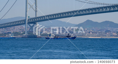 A workboat sailing under the Akashi Kaikyo Bridge A workboat sailing under the Akashi Kaikyo Bridge 140698073
