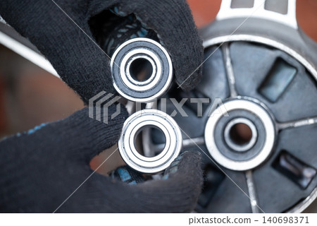 Changing bearing on rear motorbike wheel. Motorcycle repairing, maintenance of bike, changing worn out parts, details, ball bearing Changing bearing on rear motorbike wheel. Motorcycle repairing, maintenance of bike, changing worn out parts, details, ball bearing 140698371