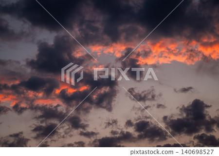 Dark dramatic clouds in sky. Sky burning with colour during sunset, vibrant colors of clouds Dark dramatic clouds in sky. Sky burning with colour during sunset, vibrant colors of clouds 140698527