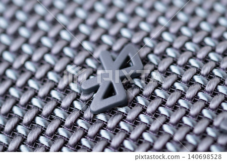 Closeup of bluetooth symbol on speaker. Using wireless bluetooth speaker concept, listening to music Closeup of bluetooth symbol on speaker. Using wireless bluetooth speaker concept, listening to music 140698528