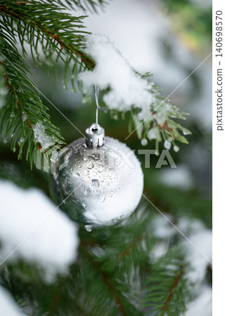 Beautiful silver ball on the branch of fir tree, covered with snow and water drops, close up, vertical shot. Christmas decoration outdoors, charmy atmosphere in the garden for winter holidays Beautiful silver ball on the branch of fir tree, covered with snow and water drops, close up, vertical shot. Christmas decoration outdoors, charmy atmosphere in the garden for winter holidays 140698570