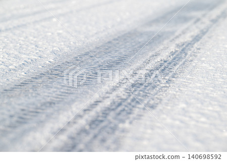 Tire tracks on an icy frozen road, close up. Winter season, slippery road, dangerous for driving Tire tracks on an icy frozen road, close up. Winter season, slippery road, dangerous for driving 140698592