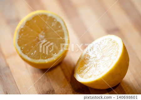 Lemon cut in two halves, close up. Fresh citrus laying on the table, yellow fruit, vitamins, good for health concept Lemon cut in two halves, close up. Fresh citrus laying on the table, yellow fruit, vitamins, good for health concept 140698601