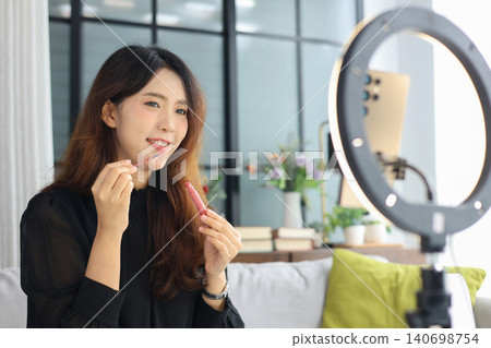 Young Asian influencer filming a beauty makeup tutorial video at home. Young Asian influencer filming a beauty makeup tutorial video at home. 140698754