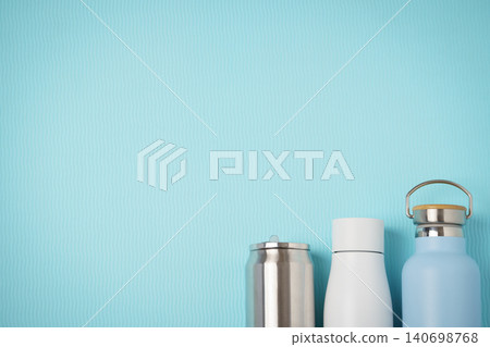 Blue and Silver Reusable Water Bottles and Thermos Trio on Textured Aqua Background Blue and Silver Reusable Water Bottles and Thermos Trio on Textured Aqua Background 140698768