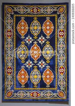 A richly colored traditional Uzbek embroidered velvet rug displayed as a wall hanging A richly colored traditional Uzbek embroidered velvet rug displayed as a wall hanging 140698805