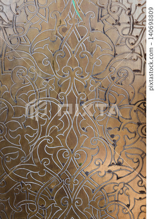 Ornate brass panel featuring engraved Islamic arabesque floral motifs Ornate brass panel featuring engraved Islamic arabesque floral motifs 140698809