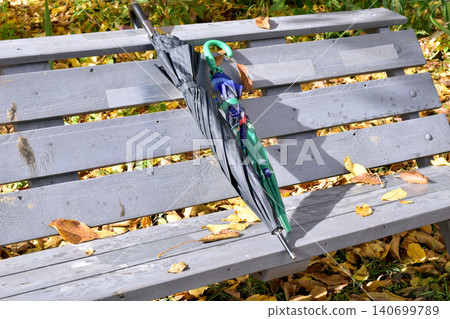 Autumn. Umbrellas are lying on a wooden bench. Autumn. Umbrellas are lying on a wooden bench. 140699789