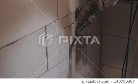 Electric Demolition Drill Breaking Block Wall, Heavy Dust Cloud, Gloved Hand Holding Power Tool, Interior Retrofit Scene, Fast Action, Rough Block Texture, Contractor Removing Material Electric Demolition Drill Breaking Block Wall, Heavy Dust Cloud, Gloved Hand Holding Power Tool, Interior Retrofit Scene, Fast Action, Rough Block Texture, Contractor Removing Material 140700367
