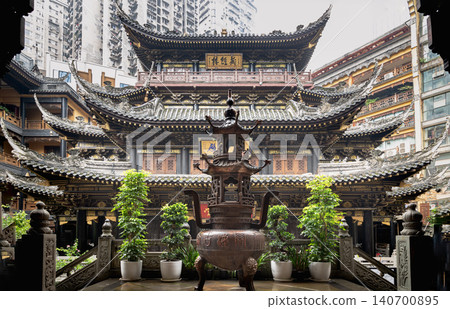 At the heart of Luohan Temple's inner courtyard stands a stately bronze censer, flanked by vibrant potted greenery. Behind it, the grand temple structure rises with layered wooden eaves that sweep At the heart of Luohan Temple's inner courtyard stands a stately bronze censer, flanked by vibrant potted greenery. Behind it, the grand temple structure rises with layered wooden eaves that sweep 140700895