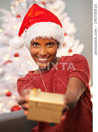 Happy, santa hat and portrait of woman with present at her home for christmas event, party or celebration. Smile, holidays and face of female person with festive xmas tree and gift on sofa at house. Happy, santa hat and portrait of woman with present at her home for christmas event, party or celebration. Smile, holidays and face of female person with festive xmas tree and gift on sofa at house. 140700918