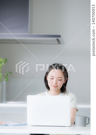 A housewife is studying in front of her computer, considering NISA (Nippon Individual Savings Account) as a way to build wealth through stocks and investment trusts. A housewife is studying in front of her computer, considering NISA (Nippon Individual Savings Account) as a way to build wealth through stocks and investment trusts. 140700953