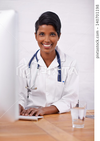 Portrait, doctor and happy woman typing on computer in hospital for healthcare career in India. Face, smile and medical professional on keyboard for wellness and online research at desk in clinic Portrait, doctor and happy woman typing on computer in hospital for healthcare career in India. Face, smile and medical professional on keyboard for wellness and online research at desk in clinic 140701198
