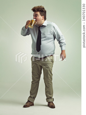 Man, face and drinking with beer for party or chug in obesity on a studio background. Young male person or plus size model with glass, mug or alcohol in satisfaction for brew or booze on mockup space Man, face and drinking with beer for party or chug in obesity on a studio background. Young male person or plus size model with glass, mug or alcohol in satisfaction for brew or booze on mockup space 140701330