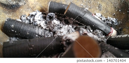 Close up of cigarette butts and ashes in a dirty ashtray showing cigarette residue and decay. 140701404