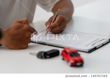 Cropped hands signing car insurance policy document with keys and toy car 140701569