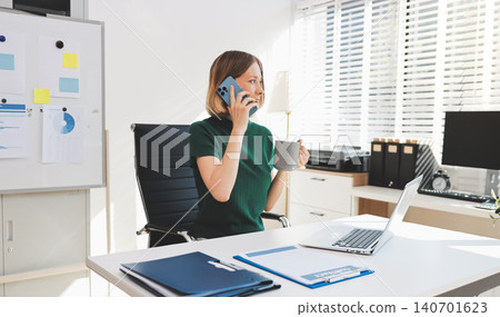 Happy female entrepreneur using smart phone in office. Happy female entrepreneur using smart phone in office. 140701623