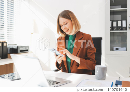 Woman smiling to herself as she works in an office Woman smiling to herself as she works in an office 140701640