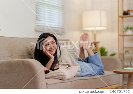 Asian woman with headphones lying on sofa at home for leisure lifestyle Asian woman with headphones lying on sofa at home for leisure lifestyle 140701795