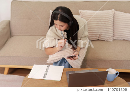 Asian woman studying with laptop and notebook on sofa at home Asian woman studying with laptop and notebook on sofa at home 140701806