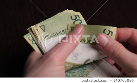 Hands Counting Polish Banknotes On Dark Desk, Closeup Showing Neat Stacks And Fingers Fanning Notes, Office Keyboard Visible, Focused Payment Processing Mood For Small Business 140703086