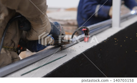 Gloved Hands Tightening Bolt On Metal Beam, Construction Technician Securing Exterior Panel With Clamp And Wrench, Closeup Of Protective Gloves And Tool Interaction, Industrial Rooftop Site, 140703158