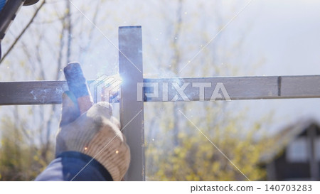 Contractor Welding Steel Frame On Construction Site Outdoors, Fullbody Posture With Helmet And Protective Gear, Sparks And Molten Bead Visible Near Base Of Post, Practical Handson Contractor Welding Steel Frame On Construction Site Outdoors, Fullbody Posture With Helmet And Protective Gear, Sparks And Molten Bead Visible Near Base Of Post, Practical Handson 140703283