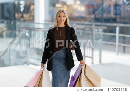 Woman holding shopping bags pointing in mall Woman holding shopping bags pointing in mall 140703338