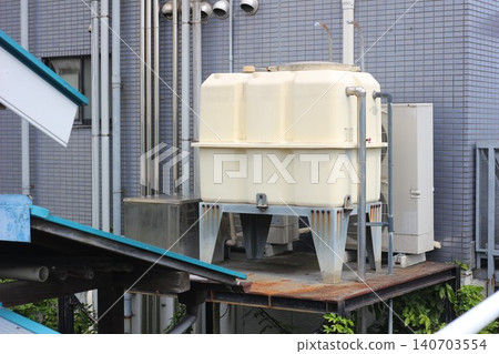 A close-up of a large water storage tank and piping installed on a platform. 140703554
