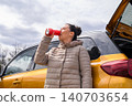 Woman drinking from can near car outdoors low angle view 140703654