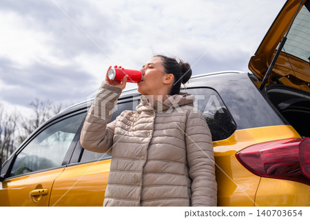 Woman drinking from can near car outdoors low angle view 140703654
