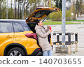 Woman relaxing at car trunk drinking beverage in parking lot 140703655