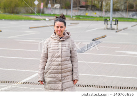 Woman standing in empty parking lot looking at camera outdoors 140703656