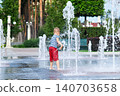 Child playing with water fountain in city square on summer day. Summer lifestyle, joy, freedom and refreshing activity in urban environment. 140703658