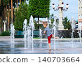 Child playing with water fountain in city square on summer day. Summer lifestyle, joy, freedom and refreshing activity in urban environment. 140703664