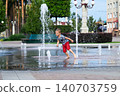 Child playing with water fountain in city square on summer day. Summer lifestyle, joy, freedom and refreshing activity in urban environment. 140703759