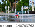 Child playing with water fountain in city square on summer day. Summer lifestyle, joy, freedom and refreshing activity in urban environment. 140703762
