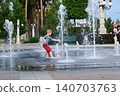 Child playing with water fountain in city square on summer day. Summer lifestyle, joy, freedom and refreshing activity in urban environment. 140703763