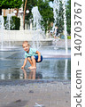 Child walking through puddle on wet playground after rain. Candid childhood moment, outdoor activity and exploration. 140703767