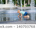 Child walking through puddle on wet playground after rain. Candid childhood moment, outdoor activity and exploration. 140703768