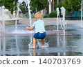 Child walking through puddle on wet playground after rain. Candid childhood moment, outdoor activity and exploration. 140703769