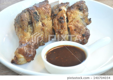 roasted chicken tight and leg with black pepper on plate dipping with spicy tamarind sauce  140704034